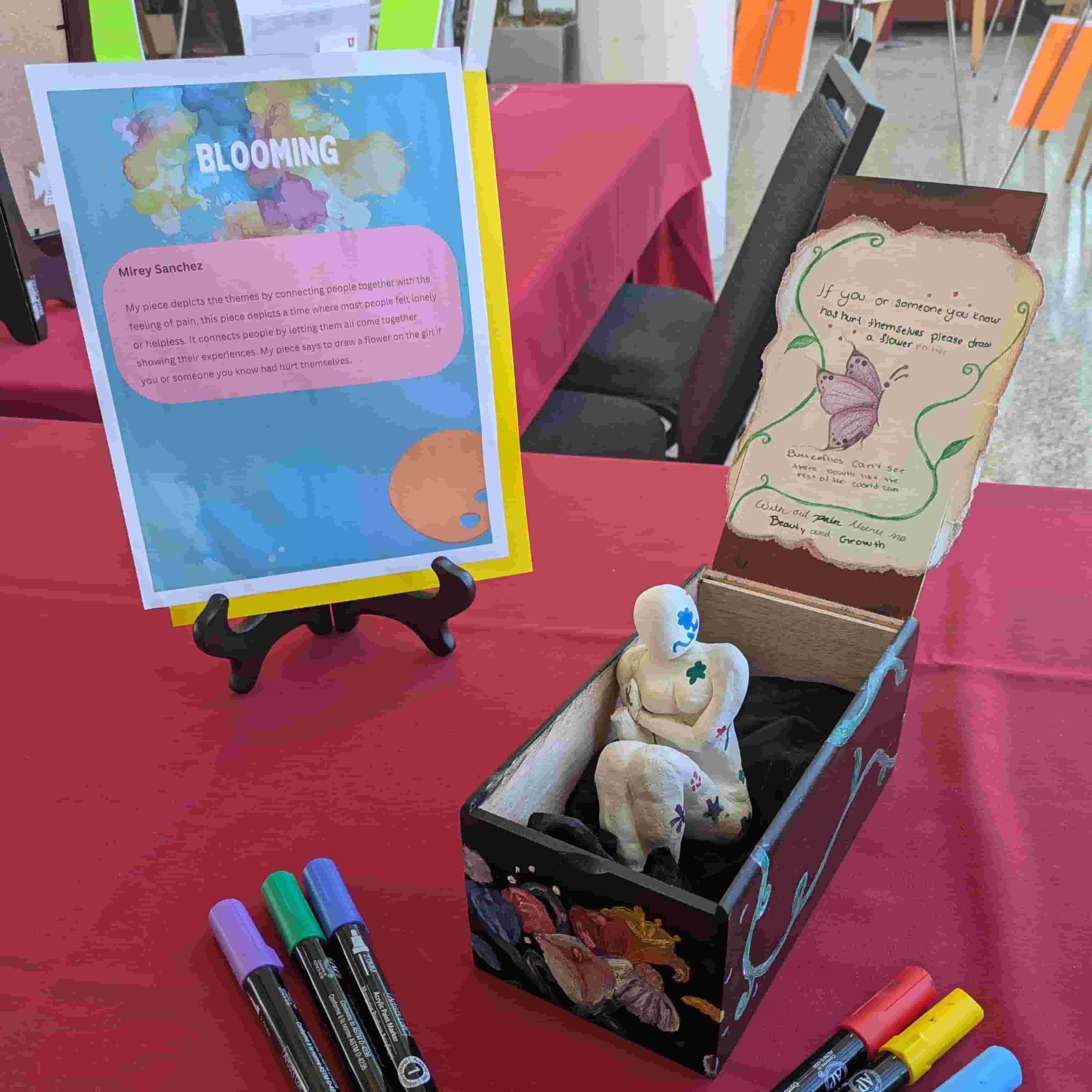 A statuette sitting in a box surrounded by markers with a descriptive plaque beside it